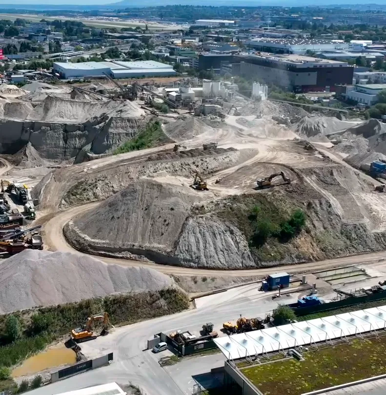 Vue aérienne d'un site d'extraction de matériaux dans la zone ZIMOGA, avec engins de terrassement