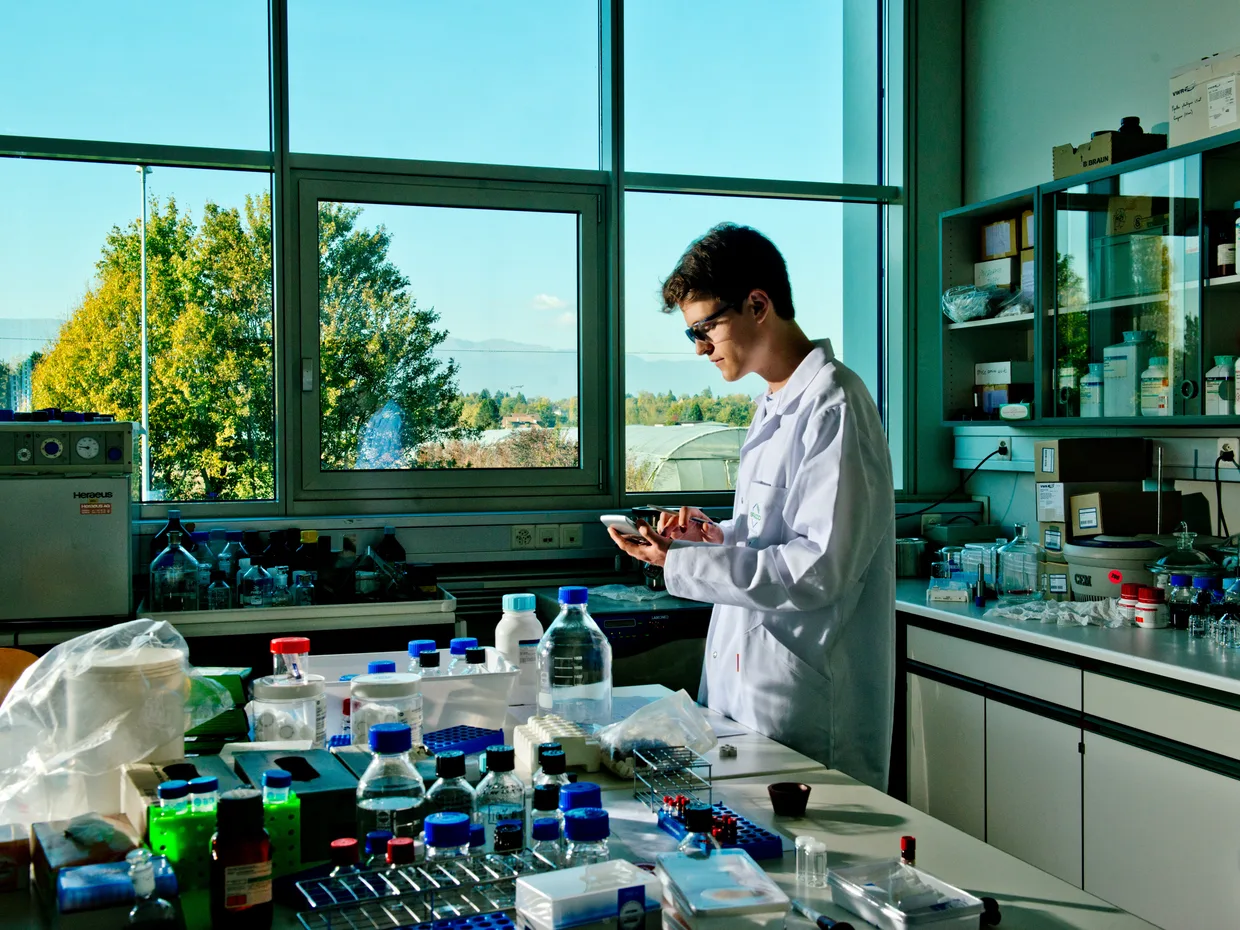 Scientifique en blouse blanche travaillant dans un laboratoire, flacons et équipements au premier plan