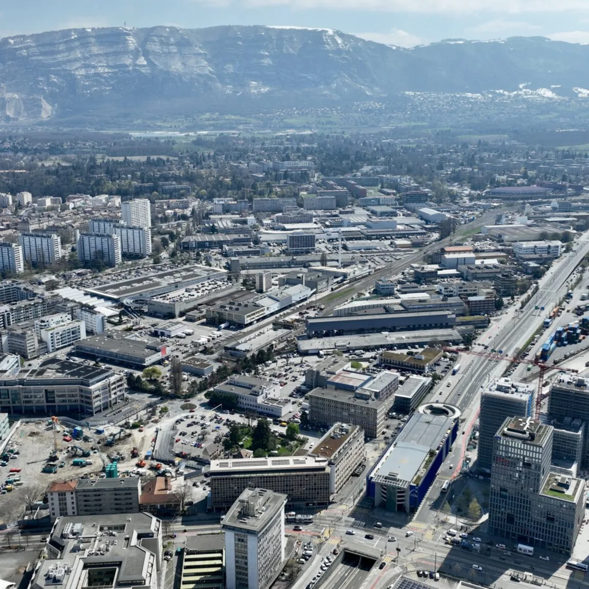 Vue aérienne de Praille-Ouest à Genève, tissu industriel dense avec les montagnes en arrière-plan